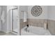 Modern bathroom featuring a soaking tub, tiled walls, and a glass-enclosed shower for a relaxing experience at 1311 Park Center Cir, Austell, GA 30168