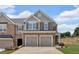 Two-story townhome showcasing a two-car garage and brick and siding exterior under a cloudy sky at 1311 Park Center Cir, Austell, GA 30168