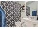 Bathroom with patterned shower curtain, sink, toilet, mirror, and storage shelves at 8767 N View Dr, Lithia Springs, GA 30122