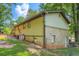 Side view of a house with a brick foundation, siding, satellite dishes, and a yard; surrounded by mature trees at 8767 N View Dr, Lithia Springs, GA 30122