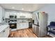 White kitchen with stainless steel appliances, marble backsplash, and wood-look laminate flooring at 8767 N View Dr, Lithia Springs, GA 30122