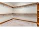 Walk-in closet with wood trim and carpet, featuring wooden shelving and rods at 402 Clyde Ct, Mcdonough, GA 30252