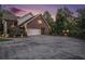 Brick home boasts an attached garage, mature trees, landscaping, and a large driveway with exterior lighting at 402 Clyde Ct, Mcdonough, GA 30252