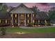 Well-lit brick home at dusk, featuring a columned entrance and landscaping at 402 Clyde Ct, Mcdonough, GA 30252