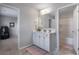 Bright bathroom with a white vanity, dual sinks, and an open doorway to a shower/tub combination at 5240 Bristlecone Pine Way, Cumming, GA 30040