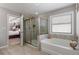 A bathtub and a glass shower in a bathroom with neutral gray walls create a spa-like experience at 5240 Bristlecone Pine Way, Cumming, GA 30040