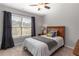 Cozy bedroom featuring a wood-framed bed, neutral bedding, and a window with dark curtains at 5240 Bristlecone Pine Way, Cumming, GA 30040