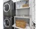 A laundry room features stacked front loading washer and dryer with a storage shelf and pull out basket at 5240 Bristlecone Pine Way, Cumming, GA 30040