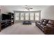 Spacious living room with a large leather sofa, entertainment center, and ample natural light from multiple windows at 5240 Bristlecone Pine Way, Cumming, GA 30040