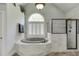 A luxurious bathroom features a soaking tub beneath an arched window and a glass-enclosed shower at 1777 Water Springs Way, Dacula, GA 30019