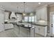 Well lit kitchen showcases white cabinets, black countertops, a stylish island with bar seating and modern pendant lighting at 1777 Water Springs Way, Dacula, GA 30019