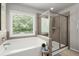 Modern bathroom showcasing a luxurious bathtub with glass shower, bright window, and tile surround at 5605 Miners Rdg, Cumming, GA 30028