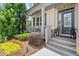 Charming front porch and entry area of a beautiful two-story home with manicured flowerbeds and shrubbery at 5605 Miners Rdg, Cumming, GA 30028