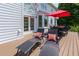 Deck furnished with a dining table, chairs and chaise lounges; a red umbrella offers shade in the backyard at 130 Hamilton Way, Roswell, GA 30075