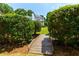 Backyard view through mature hedge showing house, deck and lush lawn and landscape at 130 Hamilton Way, Roswell, GA 30075