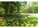 Seating area with small table and flowers with bocce court, trees and lawn in background at 130 Hamilton Way, Roswell, GA 30075