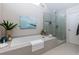 Bright bathroom features a soaking tub, a seamless glass shower, and neutral tile at 130 Hamilton Way, Roswell, GA 30075