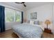 Comfortable bedroom featuring a window, ceiling fan, wood floors, and bed dressed in blue and white bedding at 130 Hamilton Way, Roswell, GA 30075