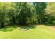 Backyard featuring a bocce court with stone edging and lush green lawn and mature trees at 130 Hamilton Way, Roswell, GA 30075