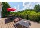 The outdoor deck is furnished with a dining table with chairs and lounge chairs with a red umbrella at 130 Hamilton Way, Roswell, GA 30075