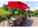 The outdoor deck is furnished with a dining table with chairs, plus extra lounge chairs and a red umbrella at 130 Hamilton Way, Roswell, GA 30075