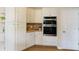 Bright kitchen features stainless double ovens, quartz countertops and white cabinets at 130 Hamilton Way, Roswell, GA 30075