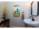 Charming powder room featuring a pedestal sink, decorative mirror, and beautiful artwork at 130 Hamilton Way, Roswell, GA 30075