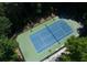 Aerial view of tennis court showcasing court's layout, surrounding trees, lighting, and nearby walkway at 130 Hamilton Way, Roswell, GA 30075