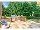 Outdoor kitchen with built-in grill, stone patio, and lush greenery creates a perfect space for entertaining at 2317 Whiting Bay Courts Nw, Kennesaw, GA 30152
