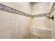 Shower with neutral tile surround, decorative border, bench and pebble tile flooring at 2317 Whiting Bay Courts Nw, Kennesaw, GA 30152