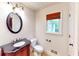 Traditional half bathroom features a decorative vanity with dark countertop, oval mirror and natural light from the window at 203 Cedar Creek Ct, Acworth, GA 30101