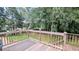 View of the backyard with a wooden deck, grassy lawn, and mature trees at 75 Maygold St, Mcdonough, GA 30253