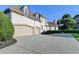 View of home exterior featuring a three-car garage, long drive way, and well maintained landscaping at 8455 Abingdon Ln, Duluth, GA 30097