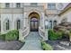 Elegant home entrance with a grand arched doorway, stone steps, and manicured landscaping at 8455 Abingdon Ln, Duluth, GA 30097