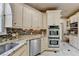 A bright kitchen featuring stainless steel appliances, including double ovens, granite counters, and tile floors at 8455 Abingdon Ln, Duluth, GA 30097
