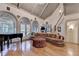 Elegant living room with a piano, curved sofa, and access to the staircase at 8455 Abingdon Ln, Duluth, GA 30097