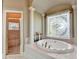 This main bathroom features a large soaking tub, a shower, and a decorative window at 8455 Abingdon Ln, Duluth, GA 30097