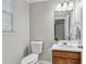 A cozy powder room featuring a vanity with a sink, toilet, and window for natural light at 303 Fox Overlook, Woodstock, GA 30188
