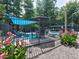Community pool with lounge chairs and umbrellas, surrounded by vibrant flowers and a secure fence at 750 Whitehall Way, Roswell, GA 30076