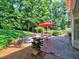 Patio features an umbrella, seating, landscaping, and a wooded backdrop at 750 Whitehall Way, Roswell, GA 30076