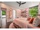Sunlit bedroom with pink walls, floral accents, a ceiling fan, and a view into the adjoining bathroom at 3891 Wieuca Rd, Atlanta, GA 30342