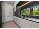 Stylish kitchen featuring sleek white cabinetry, a black countertop, and a window with a scenic outdoor view at 3891 Wieuca Rd, Atlanta, GA 30342