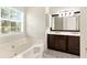 Bathroom featuring a garden tub, double sink vanity, and a large window for natural light at 5745 Crystal Springs Way, Powder Springs, GA 30127
