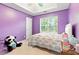 Cute purple bedroom with a tray ceiling, a window, and soft natural light at 5745 Crystal Springs Way, Powder Springs, GA 30127