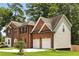 View of the two-story red brick home featuring a two-car garage and manicured landscaping at 5745 Crystal Springs Way, Powder Springs, GA 30127
