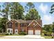 Charming two-story red brick home featuring a two-car garage, manicured landscaping, and mature trees at 5745 Crystal Springs Way, Powder Springs, GA 30127