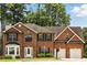 Charming two-story red brick home with a two-car garage, manicured landscaping, and mature trees at 5745 Crystal Springs Way, Powder Springs, GA 30127