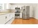 Well-lit kitchen features stainless steel appliances, white cabinetry, and hardwood floors at 5745 Crystal Springs Way, Powder Springs, GA 30127