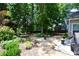 View of the landscaped backyard featuring a gravel area, lush greenery, and mature trees at 340 Channings Lake Dr, Lawrenceville, GA 30043