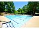 Large community pool with lounge chairs surrounded by mature trees on a sunny day at 340 Channings Lake Dr, Lawrenceville, GA 30043